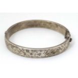 A silver bracelet of bangle form with engraved floral and acanthus scroll decoration.