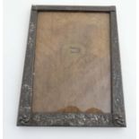 An early 20thC planished pewter photograph frame with cast and planished decoration,