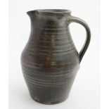 A large late 20thC Studio Pottery jug in mottled grey having ribbed decoration and impressed