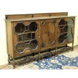 A 1920s oak glazed cabinet with ebony cabochon and carved William & Mary style stretchers 92" wide
