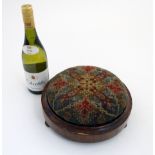 A Victorian walnut stool of circular form with needlework detail.