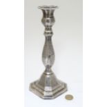 A white metal candlestick with engraved decoration.