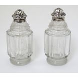 A pair of glass pepperettes with 19thC silver tops.