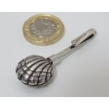 A silver napkin clip with scallop shell formed grips. Hallmarked London 2000 maker CCP.