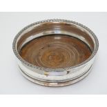 A silver plate coaster with turned wooden base.