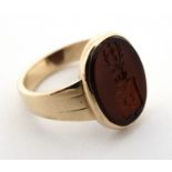 A yellow metal signet ring with set with oval cornelian seal with engraved armorial crest