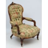 A Victorian walnut button back upholstered open arm chair with inlay and carved decoration and