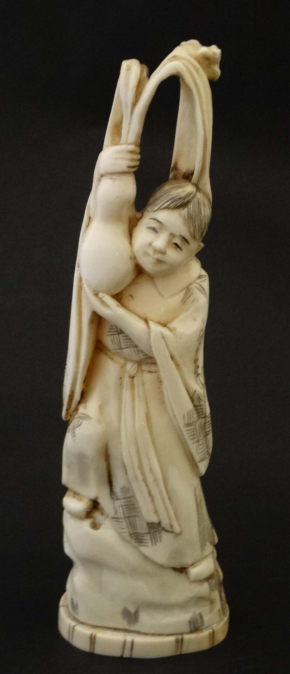 An Japanese ivory Meiji okimono formed as a figure standing with a gourd. Signed under.