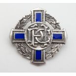 A hallmarked silver brooch of cross and laurel chaplet form with blue enamel decoration and central