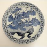 A large blue and white Japanese charger decorated with figures amidst scrolling cloud making