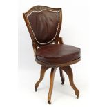 A c.1900 swivel office chair with shield shaped back with burgundy ostrich leather upholstery.