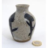 A small studio pottery vase with navy blue decoration on a mottled grey ground,