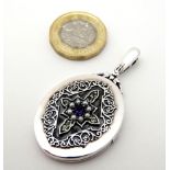 A Sterling silver locket set with peridot, amethyst and seed pearls.