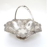 A silver plated pedestal cake basket with floral fruit and C-scroll decoration and swing handle.