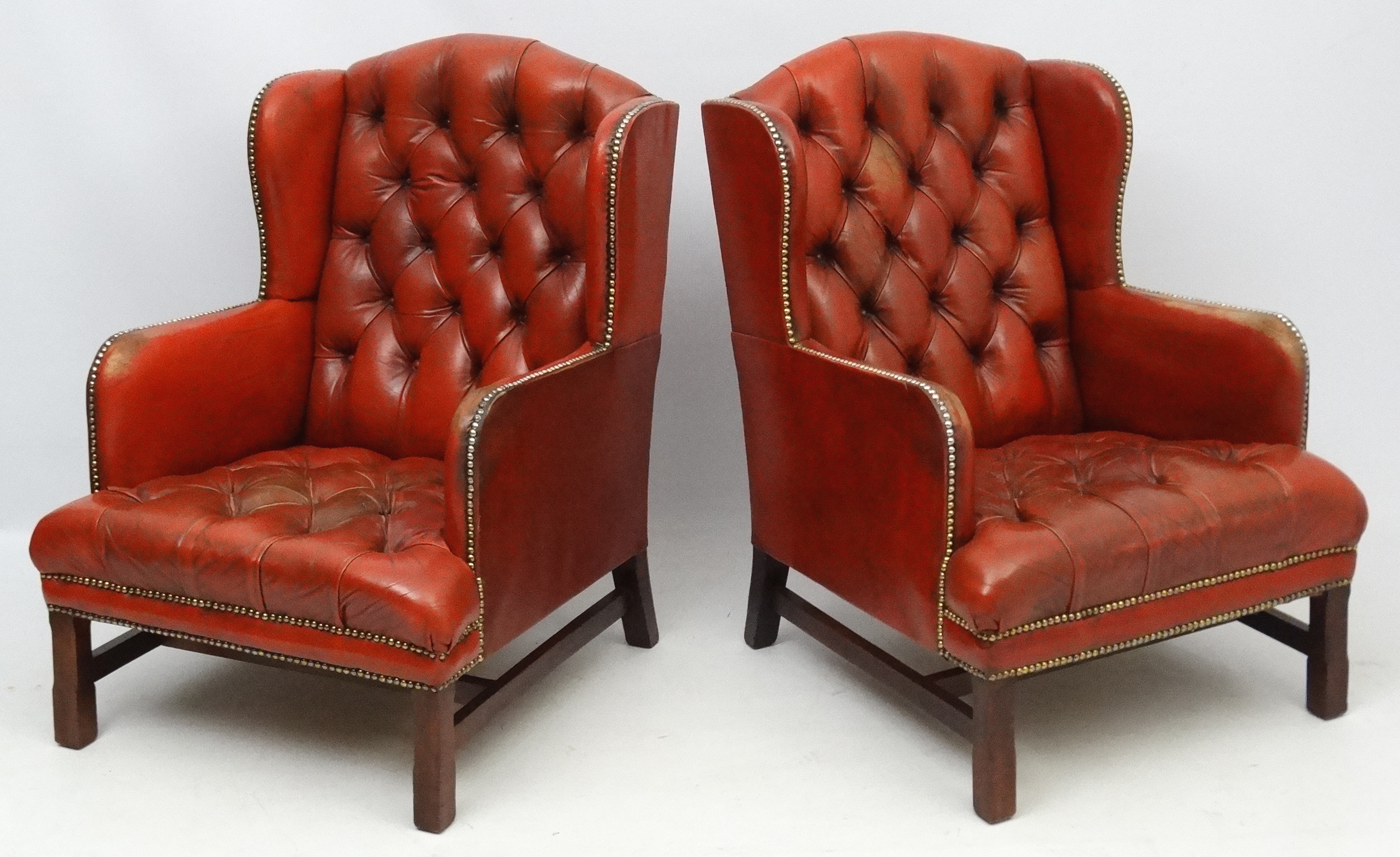 A pair of 20thC red leather wing back armchairs with button back and brass stud decoration 36 1/2"