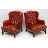 A pair of 20thC red leather wing back armchairs with button back and brass stud decoration 36 1/2"