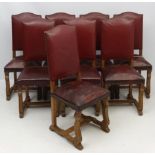 A set of 8 Burgundy leather bow back oak dining chairs with brass stud decoration and sprung seats