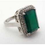 A silver ring set with green stone bordered by white stones CONDITION: Please Note