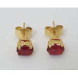 A pair of gilt metal stud earrings set with red stones.