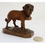 A late 19thC carved Swiss carved lime wood figure of a St Bernard dog with inset glass eyes and