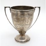A silver trophy cup with two handles and engraved ' Expandite Social and Sport Club " The Watson