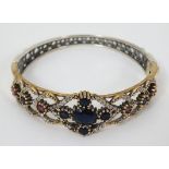 A silver bracelet with silver gilt decoration and set with blue red and white stones