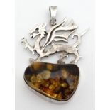 A silver pendant set with amber cabochon surmounted by a dragon.