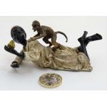 A 21st Novelty cold painted bronze figure group depicting a recumbent African figure wearing a fez