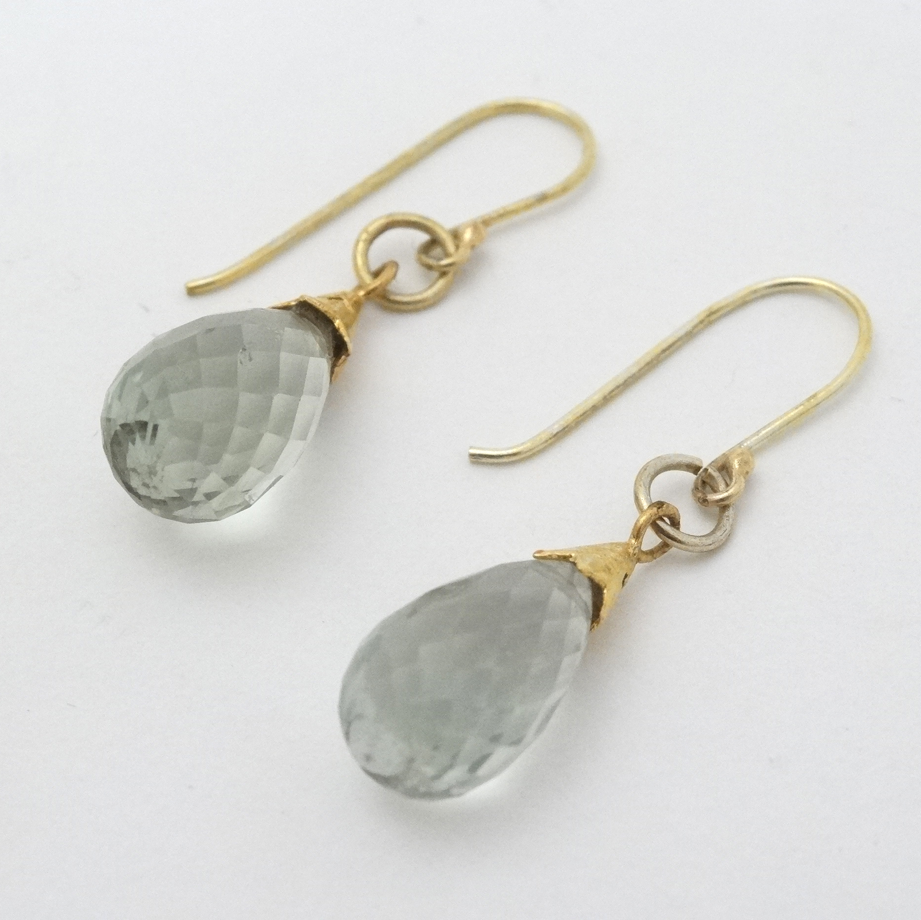 A pair of yellow metal drop earnings set with semi precious stone drops cut facet cut detail