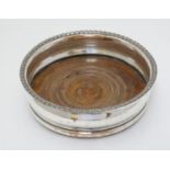 A silver plate coaster with turned wooden base.