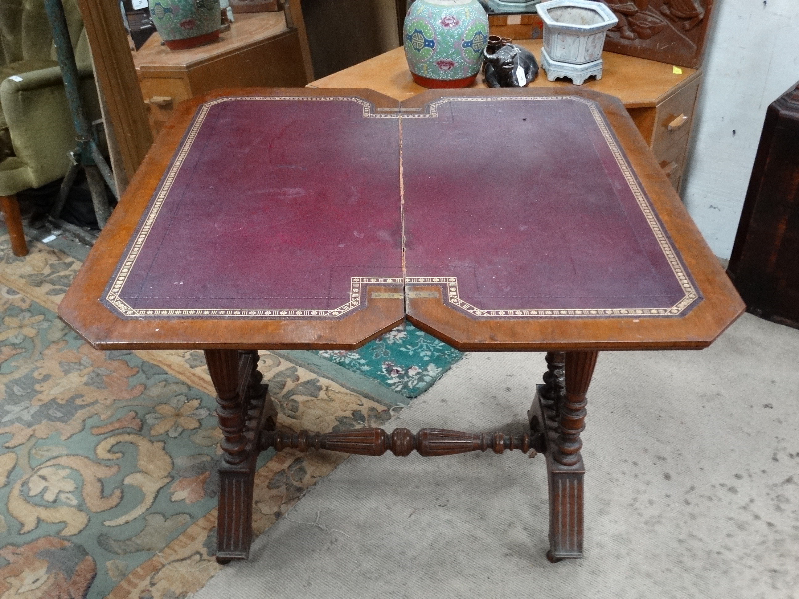 A Victorian stained oak card table with fold over and twist top and gold tooled burgundy leather