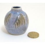 A small studio pottery vase , decorated in shades of green on a blue ground,