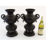 A pair of patinated bronze sensor / vases with dragon handles and decorated with raptors and