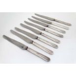 A set of 8 table knives with white metal handles.