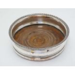 A silver plate coaster with turned wooden base.