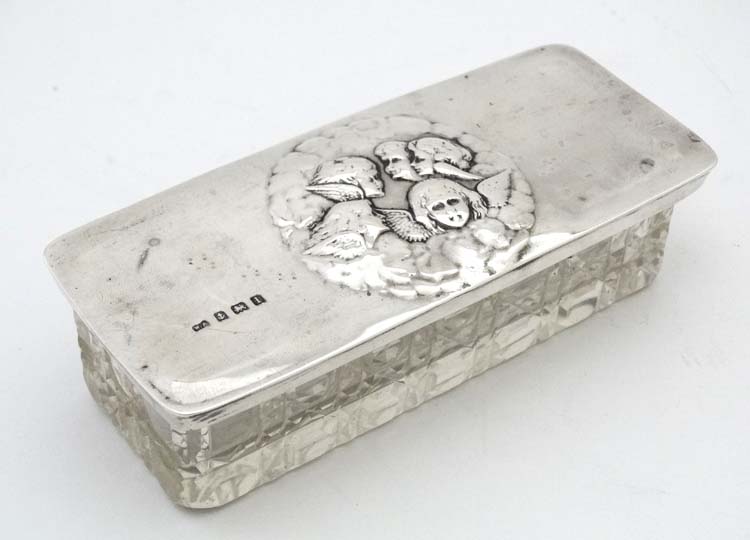 A cut glass dressing table pot with silver top having embossed angel decoration.