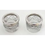 A pair of cut glass salts with silver rims hallmarked London 1918 maker Henry Perkins & Sons.