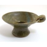 An Oriental Studio Pottery chamberstick , decorated in olive green with loop handle,