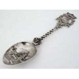 A Continental white metal spoon with Dutch pastoral scene to bowl and ornate handle with image of