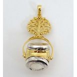 A silver pendant fob with rotating central section with locket sections and gilt decoration.