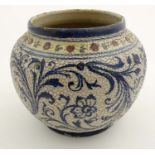 An Iznik style pottery bowl decorated in a textured finish with scrolling foliage in blue on a white