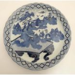 A large blue and white Japanese charger decorated with figures amidst scrolling cloud making