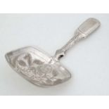 A William IV silver caddy spoon with engraved decoration to the squared bowl.