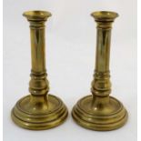A pair of 19thC heavy cast bell-metal cannon-barrel candlesticks with circular bases.