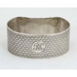 An Art Deco silver napkin ring of shaped form with engine turned decoration.