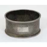 A silver napkin ring of oval form with engine turned decoration hallmarked Birmingham 1949 maker F H