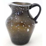 An early / mid 19thC brown glass jug with white flecked detail and rim, having loop handle.