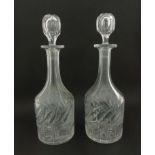 A pair of clear cut glass decanters having leaf style decoration to sides with stoppers.