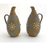 A pair of Doulton ceramic Lambeth stoneware ewers embossed with blue, green,