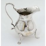 A silver cream jug on three out swept feet with loop handle hallmarked Chester 1899 maker George